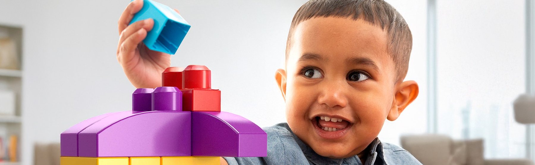 Smiling boy adding a block to a MEGA BLOKS build at home